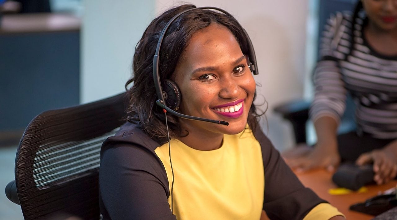 Collaboratrice souriante au téléphone avec un client