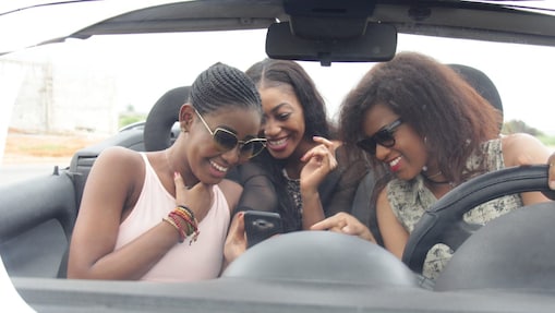 Jeunes femmes guinéennes dans une voiture en train de consulter le localisateur de station-service Shell sur leur mobile